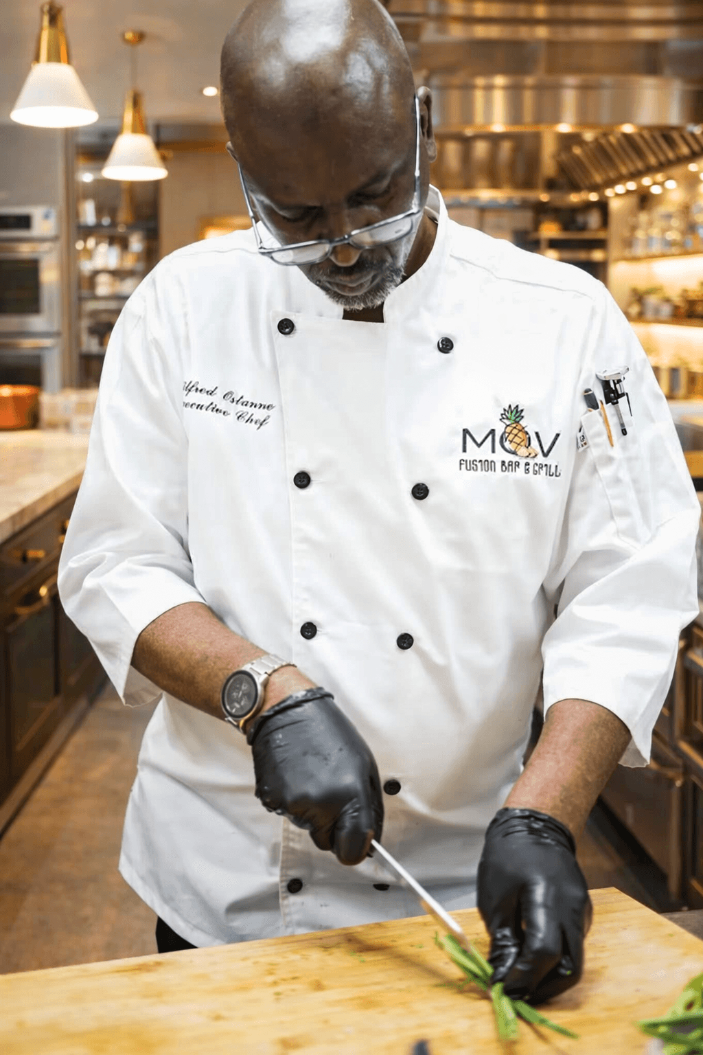 Executive Chef Wilfred Ostanne slicing scallions in the MOV Fusion Bar & Grill kitchen