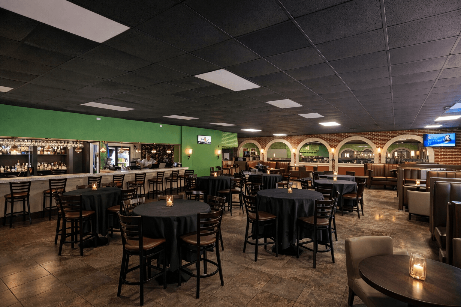 MOV Fusion Bar & Grill dining room with bar, candlelit tables, brick arches, and green accent walls — Caribbean fusion restaurant in Sunrise, Florida